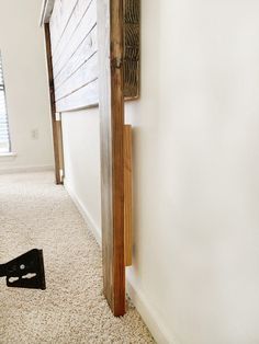 the corner of a room with a wooden door and black object on the floor next to it