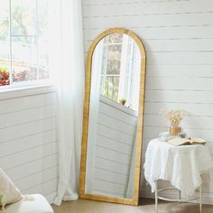 a room with a mirror, table and chair next to a window on the wall