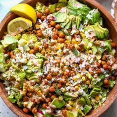 a wooden bowl filled with lettuce, chickpeas and avocado