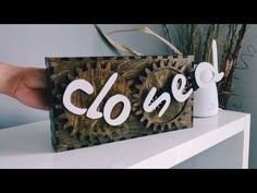 a hand holding up a wooden sign with the word closet on it and gears attached to it