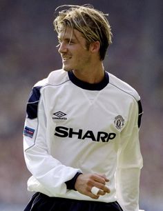 a man with long hair wearing a white and black soccer uniform is standing on the field