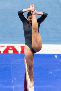 a woman standing on top of a pole while holding her hands up in the air