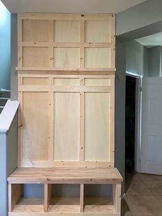 a wooden bench sitting in the middle of a room next to a wall mounted cabinet