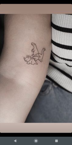 a small tattoo on the arm of a woman with a cat and dog outline in black ink