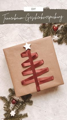 a christmas present wrapped in brown paper and tied with red ribbon, sitting next to evergreen branches