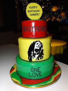 three tiered cake decorated with rastari and the words happy birthday on it