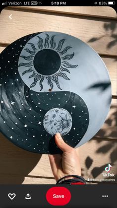 a person holding up a plate with the sun and moon painted on it's side