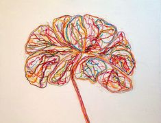 a drawing of a flower made out of colored yarn on a white wall with a red vase