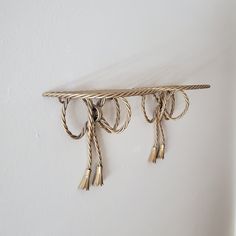 three gold hooks hanging on a white wall