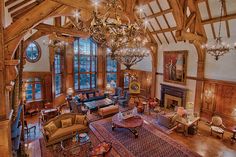 the large living room is decorated in wood and has chandeliers hanging from the ceiling