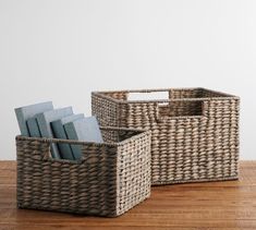 two wicker baskets sitting on top of a wooden floor next to each other with books in them