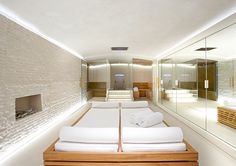 a large white bed sitting in the middle of a room next to a wall with mirrors on it