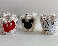 three plastic cups filled with popcorn and mickey mouse faces