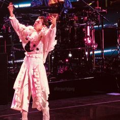 the man is performing on stage with his hands in the air