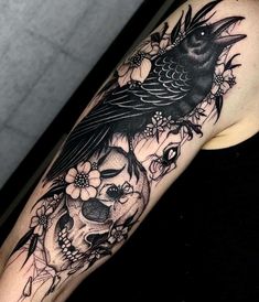 a woman's arm with a bird and skull tattoo on it