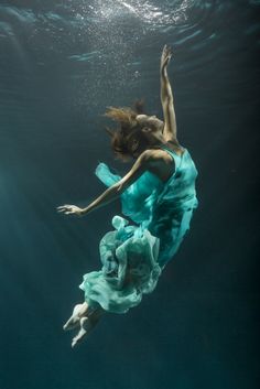 a woman in a blue dress floating under water