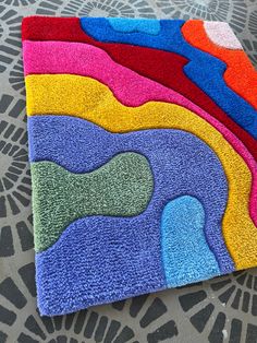 a multicolored rug on the floor with an abstract design in the middle and bottom