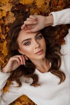 a beautiful young woman laying on top of leaves