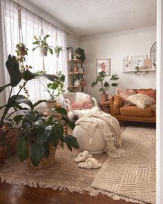 a living room filled with lots of plants next to a couch and chair on top of a rug