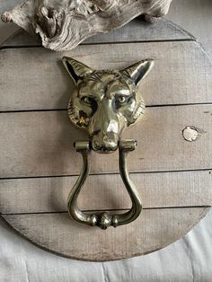 a metal dog head mounted to the side of a wooden door knocker on a wall