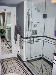 a bathroom with a walk in shower next to a white toilet and black and white tile floor