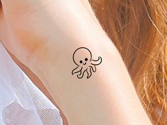 an octopus tattoo on the arm of a woman's left arm, with black ink