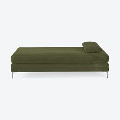 a green chaise lounger with two pillows on the back and one foot resting on it