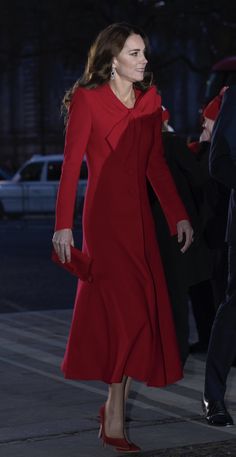 a woman in a red dress is walking down the street