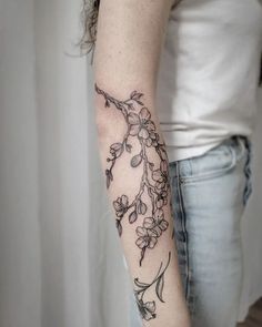 a woman's arm with flowers on it and a bird sitting on the branch