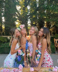 three beautiful young women standing next to each other in front of a table with cupcakes on it