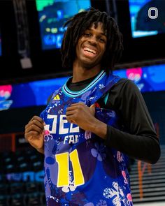 a man with dreadlocks is holding a basketball jersey