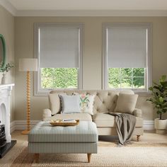 a living room filled with furniture and two windows covered in shades of white blindes