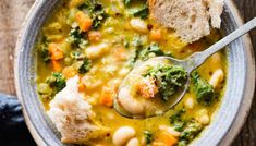 a bowl of soup with broccoli, white beans and bread on the side