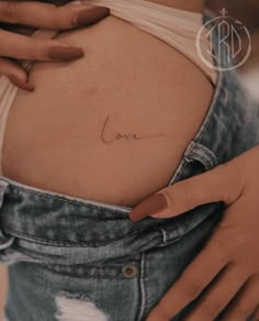 a pregnant woman's stomach with the word love written on her belly in cursive writing