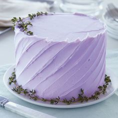 a frosted cake sitting on top of a white plate next to a knife and fork