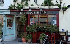 the nags head is located in an old - fashioned building with potted plants outside