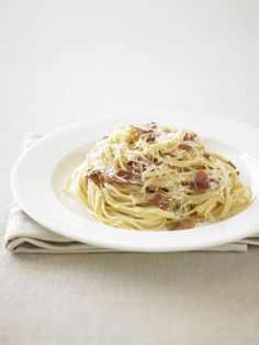 a white plate topped with spaghetti and bacon