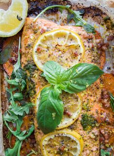 salmon with lemons, spinach and herbs on a baking sheet