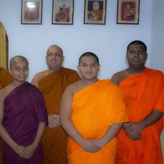 four men in orange and purple robes standing next to each other with their hands on their hips