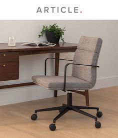 an office chair sitting on top of a wooden desk next to a book and plant