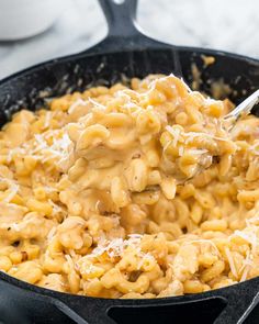 a skillet filled with macaroni and cheese being stirred with a spatula