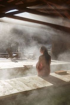 a woman is sitting in the hot tub with steam coming from her feet and back