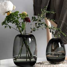 two vases with flowers in them sitting on a table