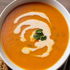 a white bowl filled with carrot soup and topped with an animal shaped piece of bread