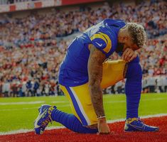 a football player kneeling on the field with his hands in his pockets and looking down