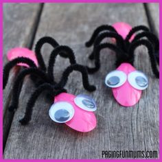 two pink and black spider decorations sitting on top of a wooden table