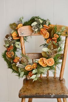 an old wooden chair with a wreath on the back and oranges hanging from it