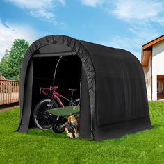 a bike is parked in the back of a black shelter on grass with a house in the background