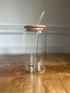 a glass jar with a wooden lid and a straw sticking out of it on a wood table