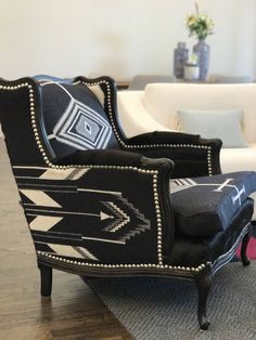 a black and white chair sitting on top of a wooden floor next to a couch